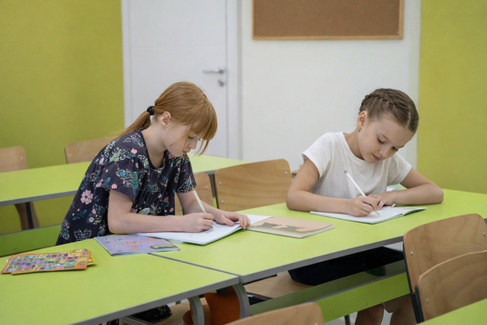 Dve učenice rade za klupama na času