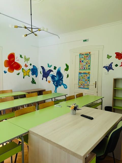 Učionica sa muralom leptira i zelenim klupama